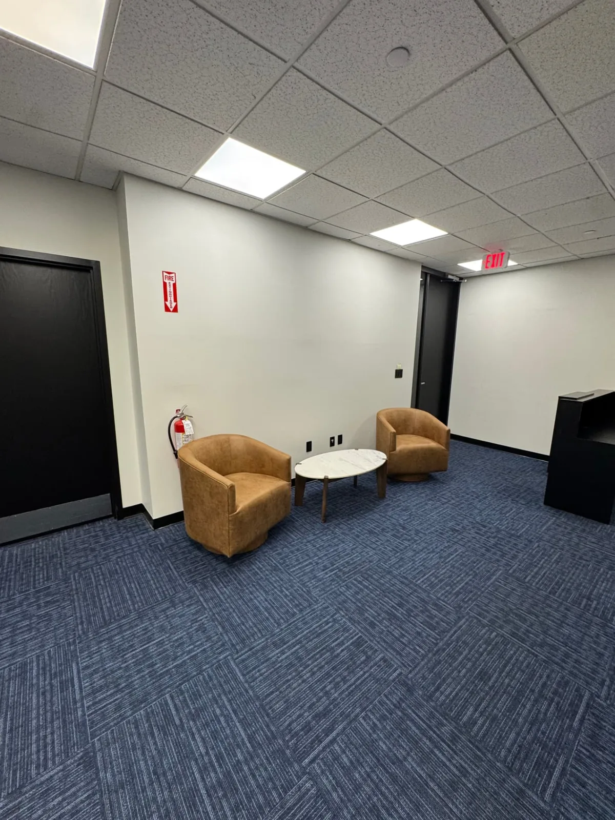 Reception lounge at Shine Wellness & Recovery in Saugus with two tan swivel chairs, a marble side table, and a check-in desk