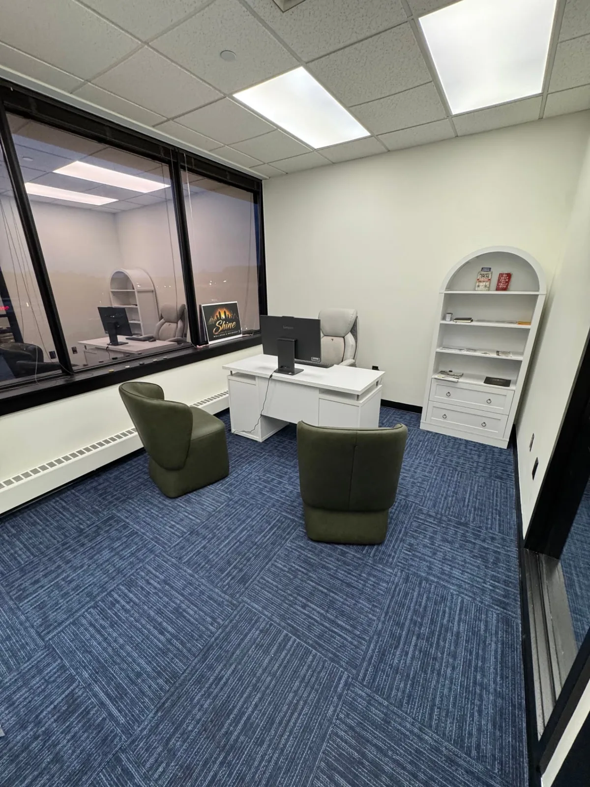 Private counseling office at Shine Wellness & Recovery with two green armchairs, a desk, and a Shine logo sign